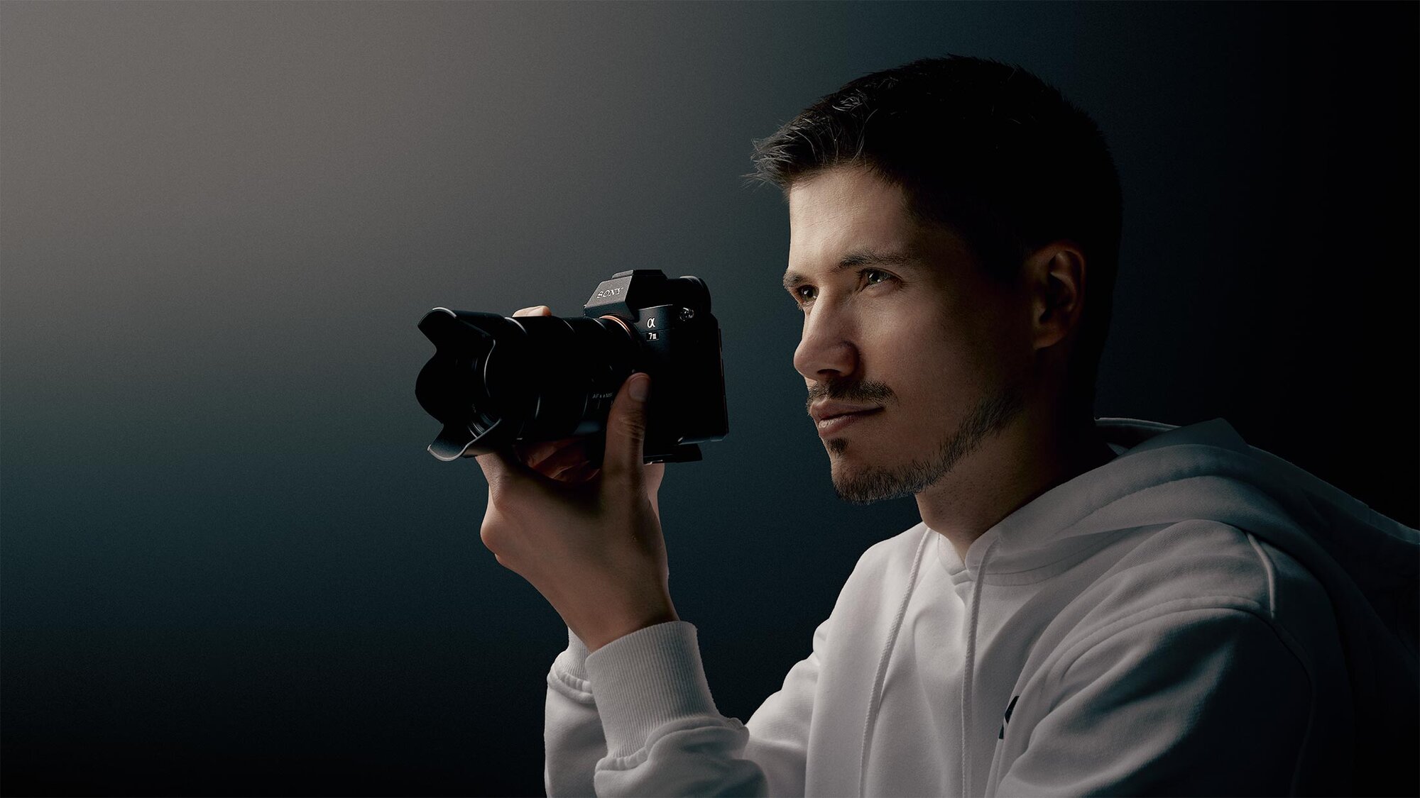Dominik Bingel mit Kamera vor dunklem Hintergrund
